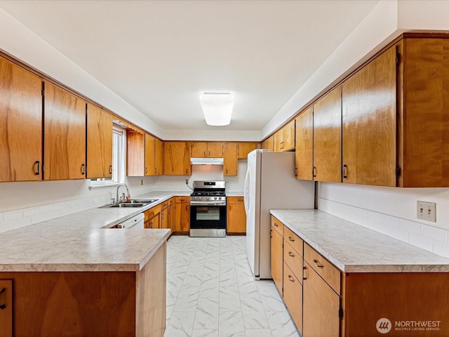 6702 120th St E, Puyallup, WA 98373 - kitchen featuring stainless steel range with gas cooktop, light countertops, brown cabinets, freestanding refrigerator, and under cabinet range hood