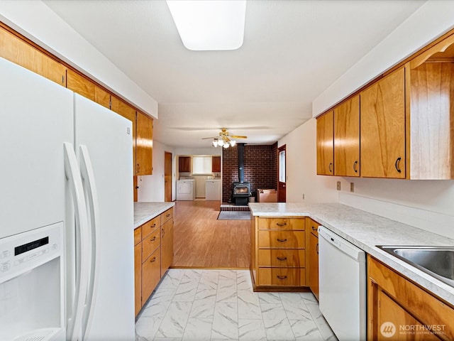 6702 120th St E, Puyallup, WA 98373 - kitchen featuring white appliances, a wood stove, light countertops, open floor plan, and brown cabinetry