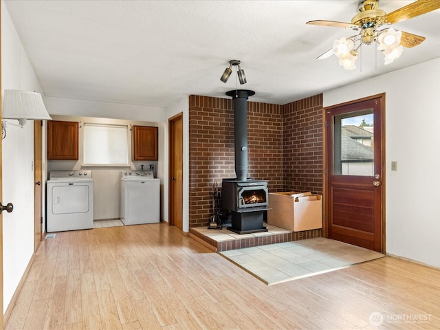 6702 120th St E, Puyallup, WA 98373 - unfurnished living room with washer and clothes dryer, light wood-style floors, a wood stove, and ceiling fan