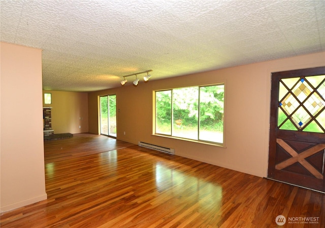 3428 99th Ave NE, Lake Stevens, WA 98258 - unfurnished living room featuring a baseboard radiator, wood finished floors, a textured ceiling, and rail lighting
