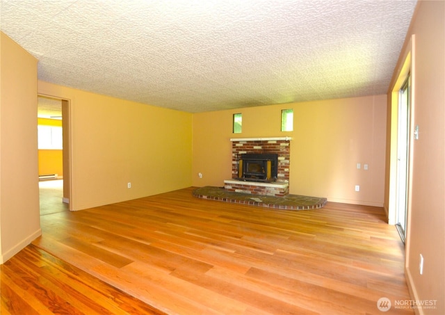 3428 99th Ave NE, Lake Stevens, WA 98258 - unfurnished living room featuring wood finished floors, a baseboard radiator, a fireplace, and a textured ceiling