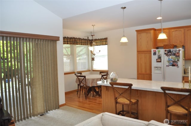 1750 Grand Ave, Mount Vernon, WA 98274 - kitchen featuring white fridge with ice dispenser, light countertops, a breakfast bar, hanging light fixtures, and carpet