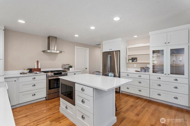 3200 SE Balboa Dr, Vancouver, WA 98683 - kitchen featuring wall chimney exhaust hood, appliances with stainless steel finishes, light wood finished floors, light countertops, and white cabinets