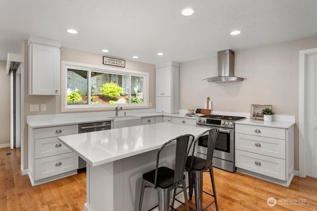 3200 SE Balboa Dr, Vancouver, WA 98683 - kitchen featuring stainless steel appliances, wall chimney exhaust hood, a breakfast bar, light countertops, and recessed lighting