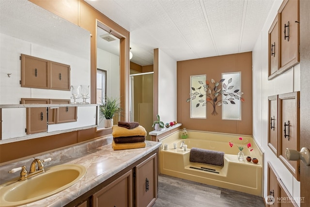 4707 Black Lake Belmore Rd SW Unit 50, Olympia, WA 98512 - full bathroom with wood finished floors, a garden tub, vanity, a shower stall, and a textured ceiling