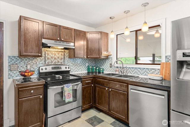 707 Kenwood St N, Omak, WA 98841 - kitchen with stainless steel appliances, under cabinet range hood, dark countertops, and tasteful backsplash