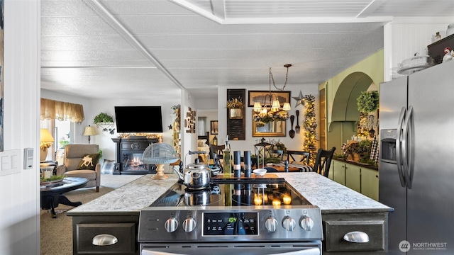 3324 W 19th Ave W Unit 52, Kennewick, WA 99338 - kitchen featuring appliances with stainless steel finishes, a glass covered fireplace, carpet floors, a chandelier, and light stone countertops