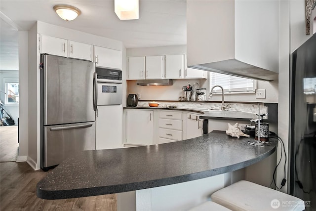 3305 207th Pl SE, Bothell, WA 98012 - kitchen with freestanding refrigerator, dark countertops, white cabinets, dark wood-type flooring, and a peninsula