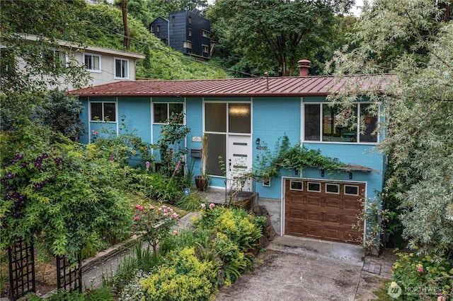 4815 46th Ave S, Seattle, WA 98118 - view of front of house featuring a standing seam roof, an attached garage, a metal roof, and concrete driveway