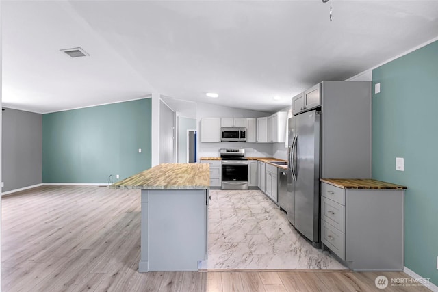700 N Reed St Unit 101, Sedro Woolley, WA 98284 - kitchen with stainless steel appliances, vaulted ceiling, gray cabinets, a kitchen island, and light countertops
