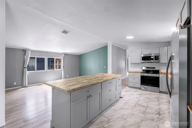 700 N Reed St Unit 101, Sedro Woolley, WA 98284 - kitchen with stainless steel appliances, wood counters, gray cabinetry, a center island, and light marble finish flooring