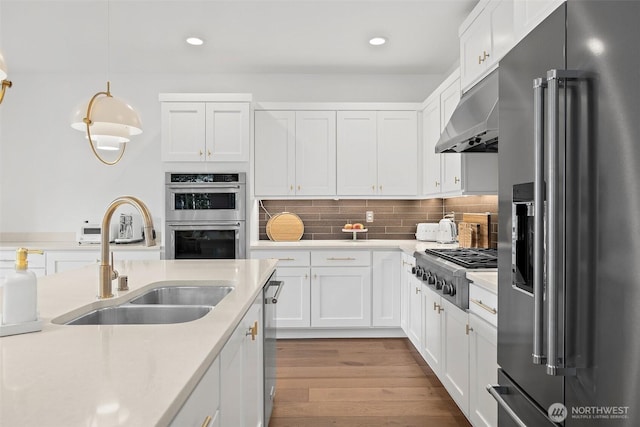 424 3rd Ln S Unit 12, Kirkland, WA 98033 - kitchen featuring stainless steel appliances, light countertops, under cabinet range hood, white cabinetry, and wood finished floors
