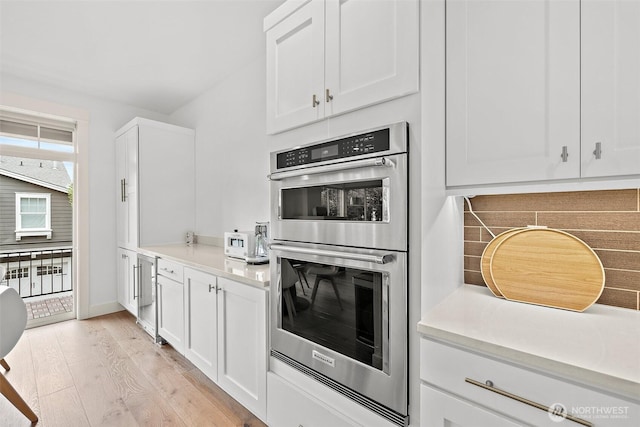 424 3rd Ln S Unit 12, Kirkland, WA 98033 - kitchen with stainless steel double oven, light wood-style flooring, white cabinets, light countertops, and beverage cooler