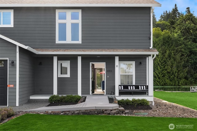 493 N Beach Dr, Port Ludlow, WA 98365 - view of front facade with covered porch, a front yard, and a shingled roof