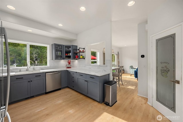 493 N Beach Dr, Port Ludlow, WA 98365 - kitchen with dishwasher, gray cabinetry, decorative backsplash, light wood-type flooring, and glass insert cabinets
