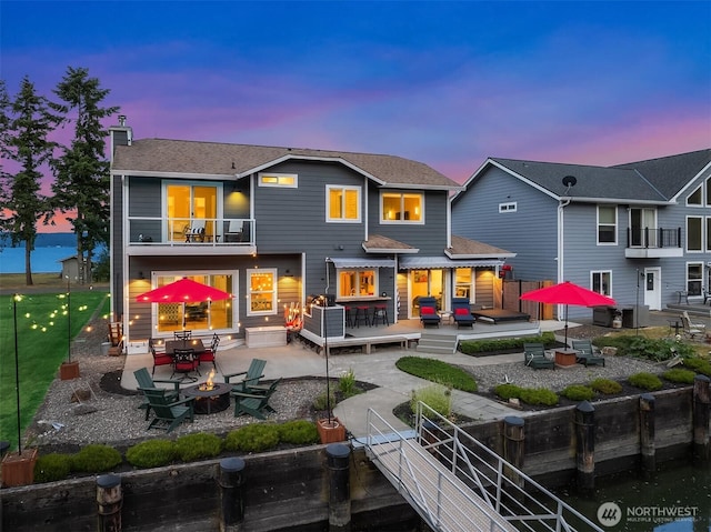 493 N Beach Dr, Port Ludlow, WA 98365 - back of house at dusk with an outdoor fire pit, a balcony, a fenced backyard, a patio, and a wooden deck