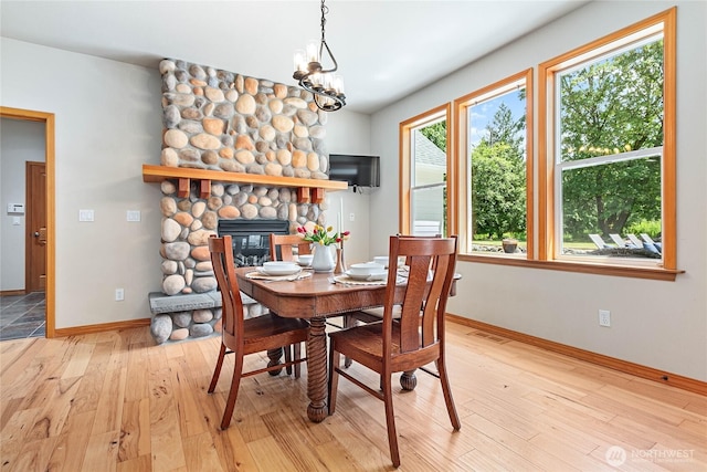 6068 E Hemmi Ln, Bellingham, WA 98226 - dining space featuring light wood-style floors, a stone fireplace, and a chandelier