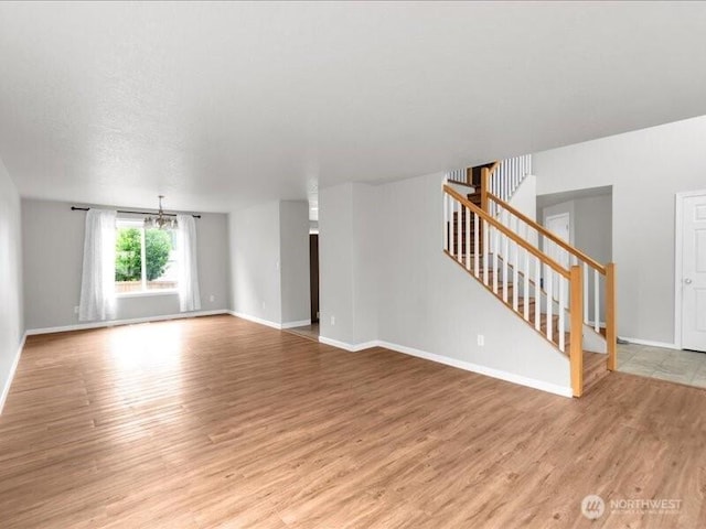 7335 33rd Ave NE, Lacey, WA 98516 - unfurnished living room with stairway, light wood-type flooring, and a chandelier