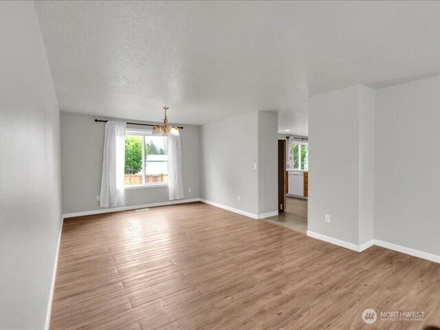 7335 33rd Ave NE, Lacey, WA 98516 - spare room with healthy amount of natural light, a chandelier, light wood-style floors, and a textured ceiling