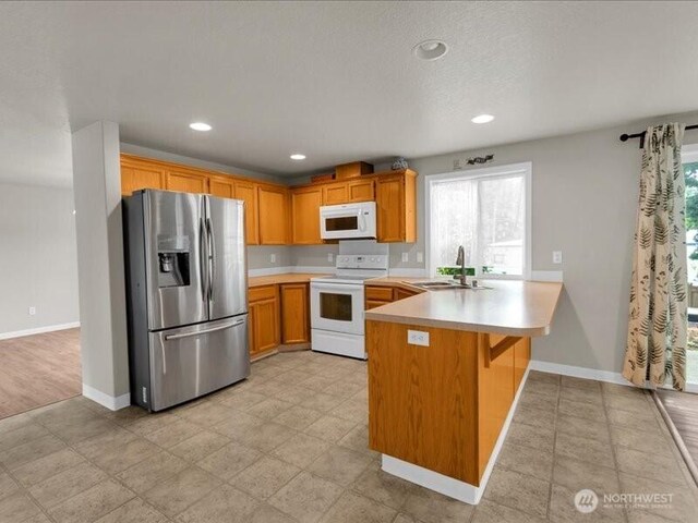 7335 33rd Ave NE, Lacey, WA 98516 - kitchen with white appliances, a peninsula, light countertops, recessed lighting, and a kitchen bar