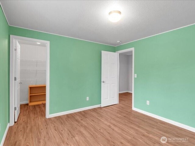 7335 33rd Ave NE, Lacey, WA 98516 - unfurnished bedroom featuring a walk in closet, wood finished floors, and a closet