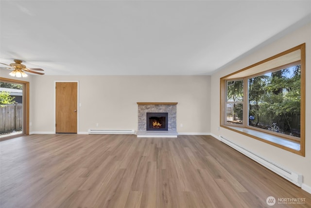 1229 SW 146th, Seahurst, WA 98168 - unfurnished living room featuring a baseboard radiator, light wood-style flooring, a lit fireplace, and ceiling fan