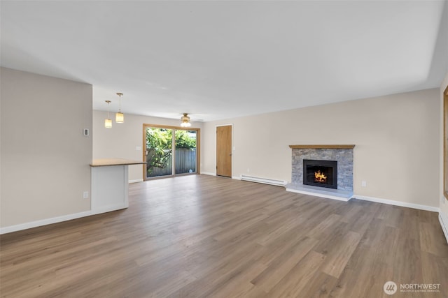 1229 SW 146th, Seahurst, WA 98168 - unfurnished living room featuring a baseboard radiator, wood finished floors, and a stone fireplace