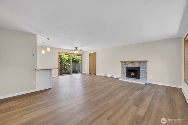 1229 SW 146th, Seahurst, WA 98168 - unfurnished living room featuring ceiling fan, wood finished floors, a fireplace, and a baseboard heating unit