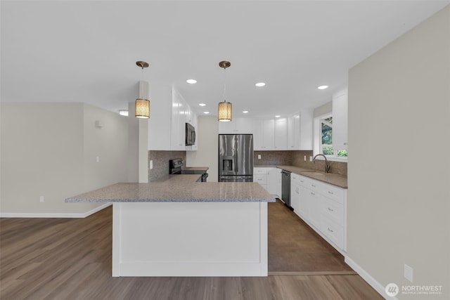 1229 SW 146th, Seahurst, WA 98168 - kitchen with appliances with stainless steel finishes, dark wood-style flooring, backsplash, a peninsula, and recessed lighting