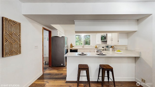 5169 Banner Rd SE, Port Orchard, WA 98367 - kitchen with appliances with stainless steel finishes, a peninsula, light countertops, white cabinetry, and dark wood finished floors