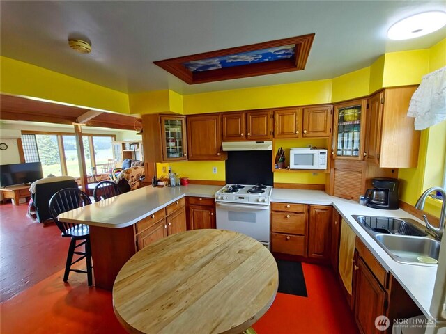 752 Parpala, Naselle, WA 98638 - kitchen featuring white appliances, a peninsula, light countertops, under cabinet range hood, and a breakfast bar area