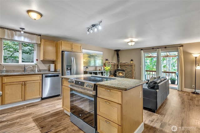 21628 SE 271st St, Maple Valley, WA 98038 - kitchen featuring stainless steel appliances, light brown cabinets, light wood-style floors, and a wood stove