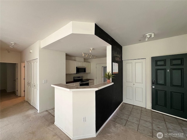 6121 Hazel Ave SE Unit A4, Auburn, WA 98092 - kitchen with appliances with stainless steel finishes, a peninsula, light colored carpet, and light tile patterned flooring