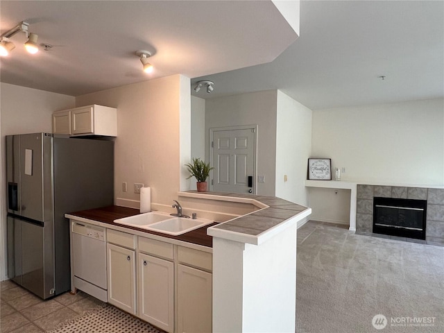 6121 Hazel Ave SE Unit A4, Auburn, WA 98092 - kitchen with white dishwasher, a peninsula, a tiled fireplace, dark countertops, and stainless steel refrigerator with ice dispenser