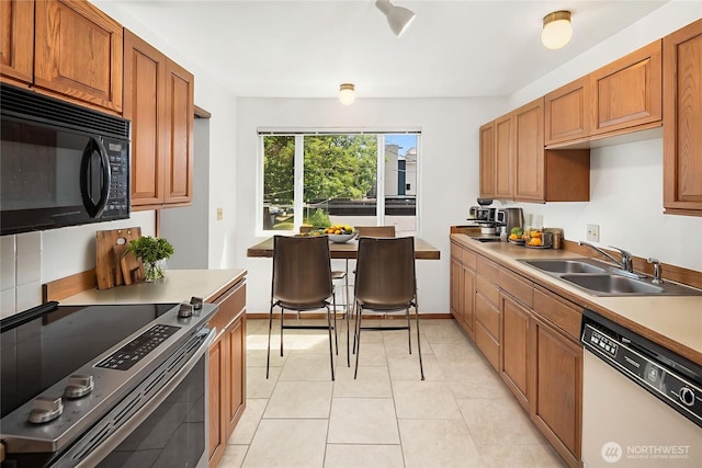 1312 S Massachusetts St Unit 202, Seattle, WA 98144 - kitchen with white dishwasher, black microwave, stainless steel electric range oven, brown cabinets, and light tile patterned flooring