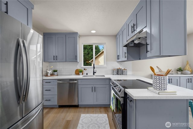 5201 S 298th Ct, Auburn, WA 98001 - kitchen featuring stainless steel appliances, under cabinet range hood, backsplash, light wood finished floors, and a textured ceiling