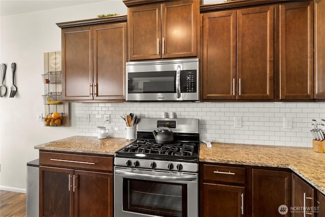 902 Van Ogle Ln NW, Orting, WA 98360 - kitchen featuring appliances with stainless steel finishes, tasteful backsplash, light stone counters, and wood finished floors