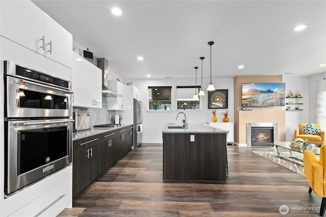 2511 124th Pl SE, Everett, WA 98208 - kitchen featuring appliances with stainless steel finishes, wall chimney exhaust hood, a center island with sink, white cabinets, and recessed lighting