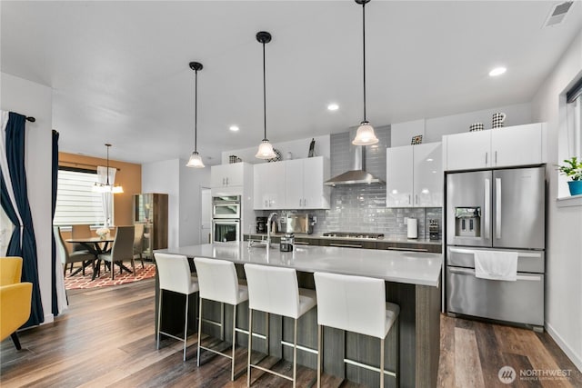 2511 124th Pl SE, Everett, WA 98208 - kitchen featuring appliances with stainless steel finishes, wall chimney range hood, dark wood-type flooring, white cabinetry, and backsplash