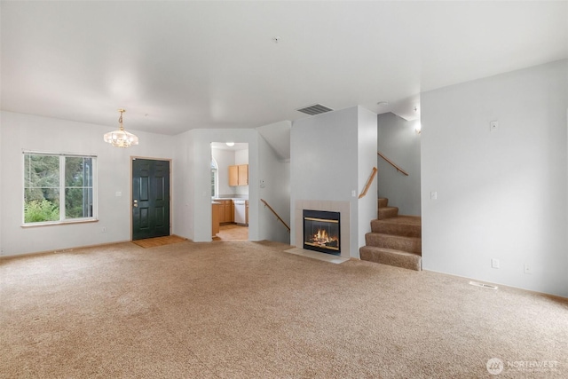 6317 Barstow Ln SE Unit 8, Lacey, WA 98513 - unfurnished living room featuring light colored carpet, a tiled fireplace, stairs, and a chandelier