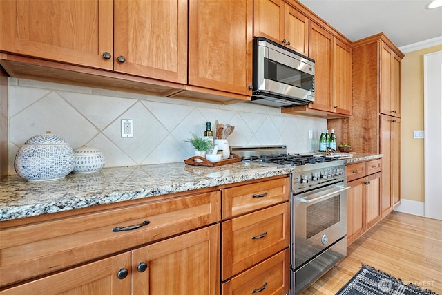219 N Tacoma Ave Unit A205, Tacoma, WA 98403 - kitchen with appliances with stainless steel finishes, light wood-style flooring, backsplash, light stone countertops, and crown molding