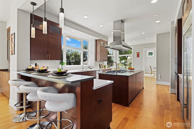 8246 W Mercer Way, Mercer Island, WA 98040 - kitchen with wall chimney exhaust hood, a center island with sink, light wood finished floors, a peninsula, and recessed lighting