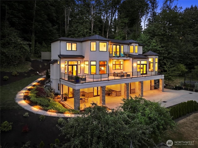 8246 W Mercer Way, Mercer Island, WA 98040 - rear view of property featuring a balcony, concrete driveway, stucco siding, a patio area, and a metal roof