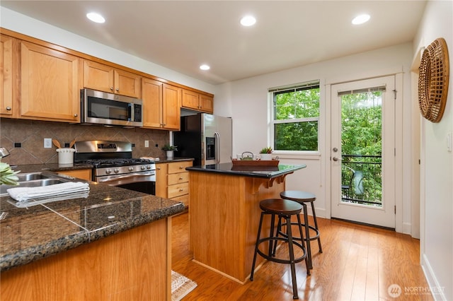 2674 SW Sylvan Heights Dr, Seattle, WA 98106 - kitchen with stainless steel appliances, light wood-style floors, tasteful backsplash, a kitchen island, and recessed lighting