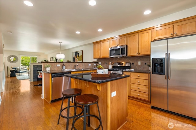 2674 SW Sylvan Heights Dr, Seattle, WA 98106 - kitchen with stainless steel appliances, a peninsula, a center island, tasteful backsplash, and light wood-style floors