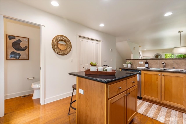 2674 SW Sylvan Heights Dr, Seattle, WA 98106 - kitchen with a kitchen breakfast bar, light wood-type flooring, recessed lighting, stainless steel dishwasher, and dark countertops