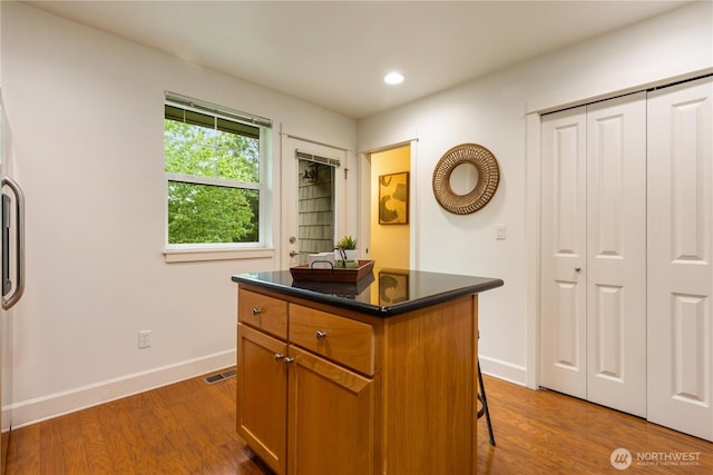 2674 SW Sylvan Heights Dr, Seattle, WA 98106 - kitchen with dark countertops, wood finished floors, recessed lighting, a center island, and a kitchen breakfast bar