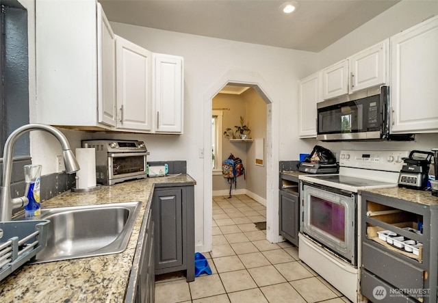 5229 S Thompson Ave, Tacoma, WA 98408 - kitchen with stainless steel microwave, white electric stove, light tile patterned floors, white cabinetry, and recessed lighting