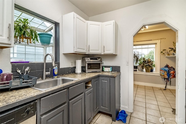 5229 S Thompson Ave, Tacoma, WA 98408 - kitchen with gray cabinetry, white cabinetry, light tile patterned floors, dishwashing machine, and arched walkways