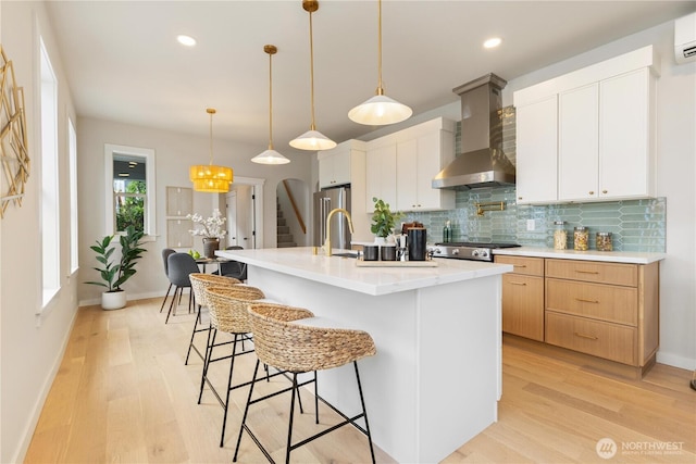 157 26th Ave, Seattle, WA 98122 - kitchen featuring wall chimney range hood, backsplash, an AC wall unit, light wood-type flooring, and a breakfast bar area